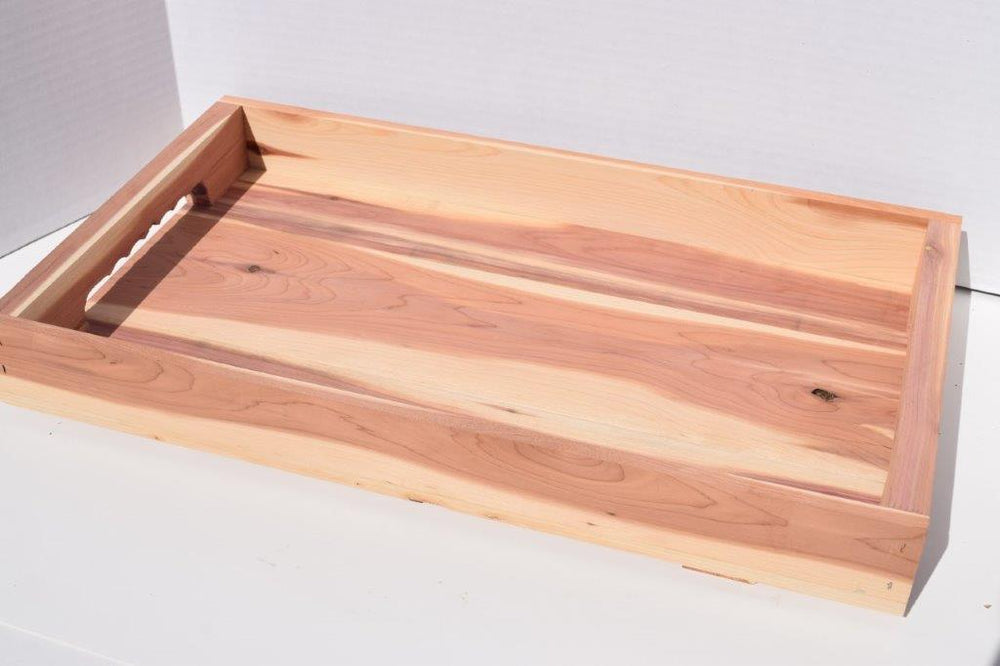 The natural cedar tray is distinguished from the others by the fingerholds in the handles.